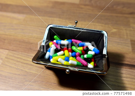 Pills in wallet on wooden background. Multicolored pharmaceutical pills, medical tablets Pills in wallet on wooden background. Multicolored pharmaceutical pills, medical tablets 77571498