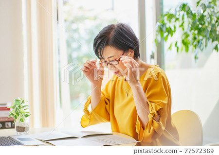 一個戴老花鏡看英文報紙的中年婦女 77572389