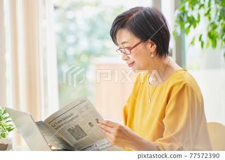 一個戴老花鏡看英文報紙的中年婦女 77572390