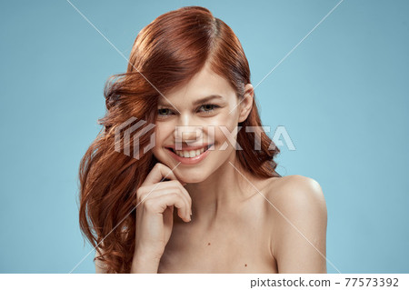 Beautiful woman curly long hair smooth hairstyle naked shoulders cosmetics care blue background Beautiful woman curly long hair smooth hairstyle naked shoulders cosmetics care blue background 77573392