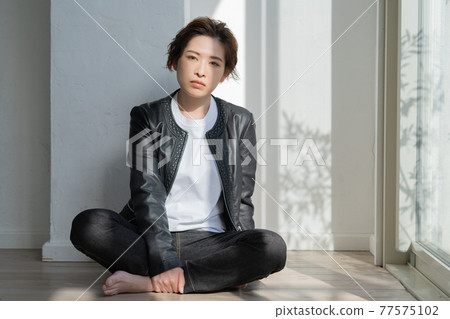 Genderless LGBT young woman in a leather jacket sitting on the floor 77575102