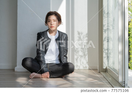 Genderless LGBT young woman in a leather jacket sitting on the floor Genderless LGBT young woman in a leather jacket sitting on the floor 77575106