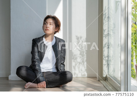 Genderless LGBT young woman in a leather jacket sitting on the floor 77575110