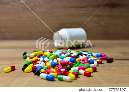 Pills from a plastic bottle on wooden background.  77576107