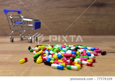 Pills in multicolored capsules on wooden background.  77576109