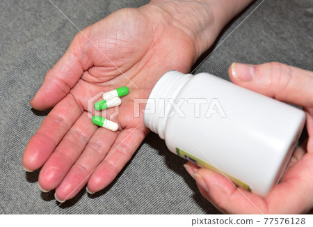 Pills in capsules in woomen hand. Medicine grade pharmaceutical tablets. Medical pill Pills in capsules in woomen hand. Medicine grade pharmaceutical tablets. Medical pill 77576128