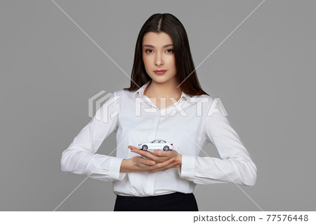 beautiful woman in shirt holding little white car beautiful woman in shirt holding little white car 77576448