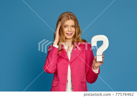blonde woman in pink jacket holding question mark blonde woman in pink jacket holding question mark 77576462