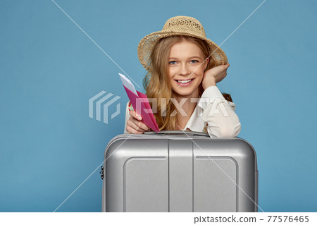 smiling blonde woman with gray suitcase, passport smiling blonde woman with gray suitcase, passport 77576465