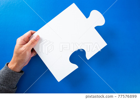man hands holding big paper white blank puzzles on a blue background, concept of business 77576899