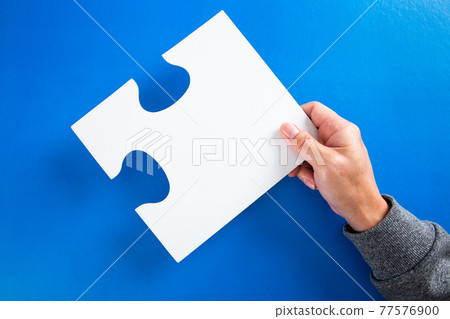 man hands holding big paper white blank puzzles on a blue background, concept of business 77576900