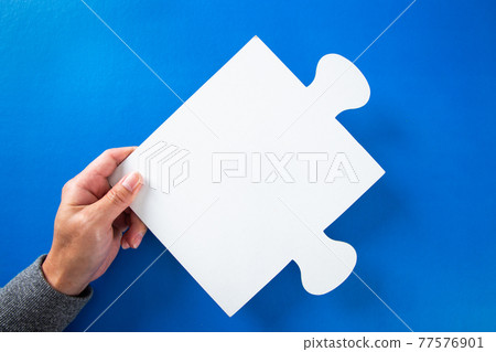 man hands holding big paper white blank puzzles on a blue background, concept of business man hands holding big paper white blank puzzles on a blue background, concept of business 77576901