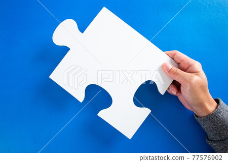 man hands holding big paper white blank puzzles on a blue background, concept of business man hands holding big paper white blank puzzles on a blue background, concept of business 77576902