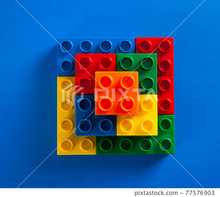 Color plastic building blocks on blue background Color plastic building blocks on blue background 77576903