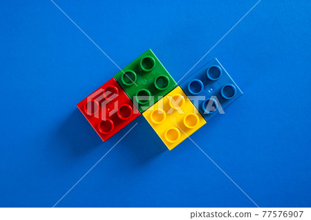 Color plastic building blocks on blue background Color plastic building blocks on blue background 77576907
