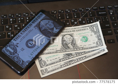 Mobile phone with the image of the president and dollars lie on the laptop keyboard, the game in the stock market Mobile phone with the image of the president and dollars lie on the laptop keyboard, the game in the stock market 77578175