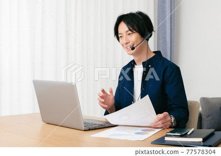 Young man having a web conference in the living room Young man having a web conference in the living room 77578304