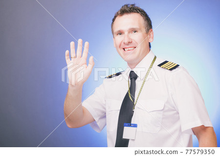 Smiling pilot waving his hand 77579350