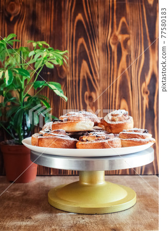 Puff pastry cakes curl with powdered sugar on top. A close-up of a bakery product. Confectionery work and customer service. A treat on a tray. 77580183