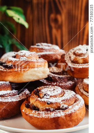 Puff pastry cakes curl with powdered sugar on top. A close-up of a bakery product. Confectionery work and customer service. A treat on a tray. 77580185