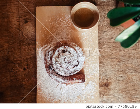 Puff pastry cakes curl with powdered sugar on top. A close-up of a bakery product. Confectionery work and customer service. A treat on a tray. 77580189