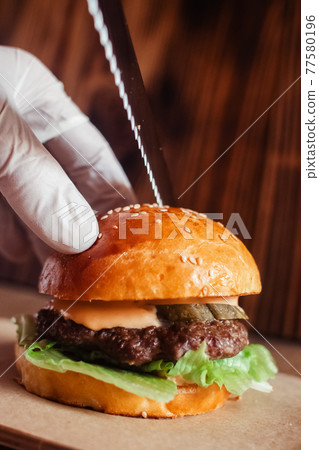 Mini burger on a stand close-up. Children fast food in a restaurant or cafe. Macro photo of burger ingredients with meat and vegetables. Eco burgers for children 77580196