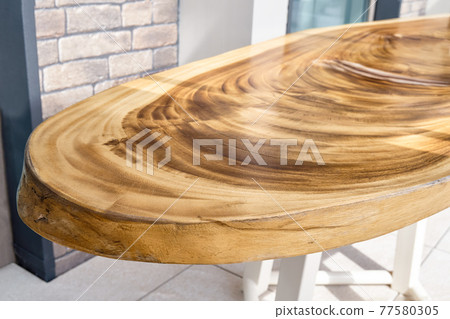 Dining table of live edge suar wood slab on metal carcass in yard 77580305