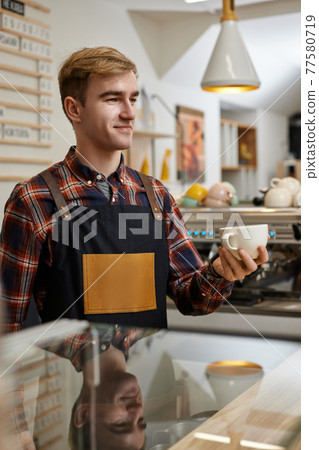 male waiter in apron holding cup of hot drink male waiter in apron holding cup of hot drink 77580719
