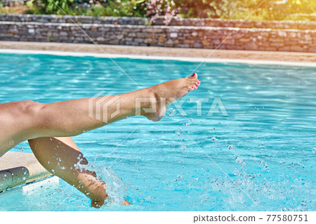 Female barefoot legs in pool splashing in sunlight in motion. Summertime moments concept Female barefoot legs in pool splashing in sunlight in motion. Summertime moments concept 77580751