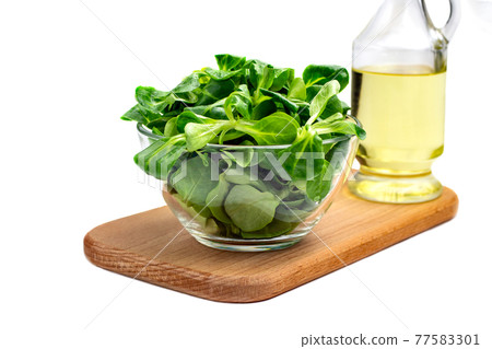 Mung bean salad leaves, corn salad in a glass bowl on a wooden board, isolate. Fresh blend of green washed leaves and vegetable oil (Valerianella locusta). Diet and healthy food concept. Fogerlsalat Mung bean salad leaves, corn salad in a glass bowl on a wooden board, isolate. Fresh blend of green washed leaves and vegetable oil (Valerianella locusta). Diet and healthy food concept. Fogerlsalat 77583301