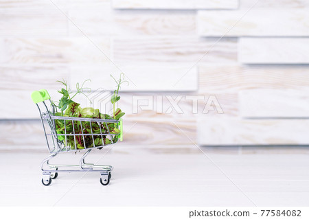 Fresh eco greens delivery concept, young microgreens in a shopping basket on a wooden table 77584082