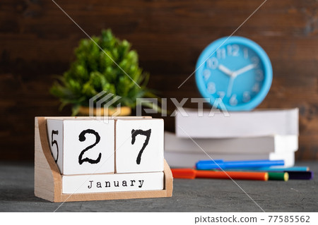 January 27th. January 27 wooden cube calendar with blur objects on background. 77585562