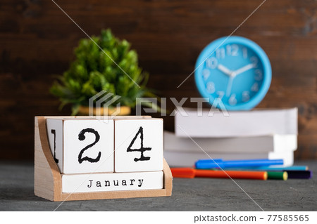 January 24th. January 24 wooden cube calendar with blur objects on background. 77585565
