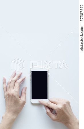 Female hand white background operating a smartphone Female hand white background operating a smartphone 77587872