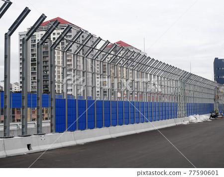 SELANGOR, MALAYSIA - JULY 5, 2020: Noise barriers are installed along the vehicle lane bordering the residence to prevent noise pollution to the surrounding locals. 77590601
