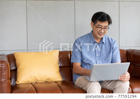 asian senior man using computer laptop at home 77591294