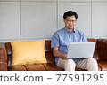 asian senior man using computer laptop at home 77591295