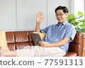 senior asian man say hi and talking with his family/friends via digital tablet 77591313