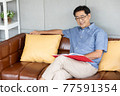 senior asian man reading book on sofa 77591354