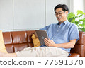 senior asian man using digital tablet on sofa 77591370
