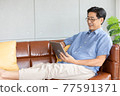 senior asian man using digital tablet on sofa 77591371