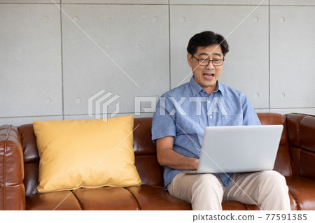 asian senior man using computer laptop at home 77591385