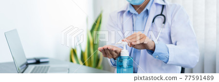 Medical concept a male doctor wearing mask and using hand sanitizer alcohol gel for preventing against infection of Coronavirus (Covid-19) outbreak at his modern clinic 77591489