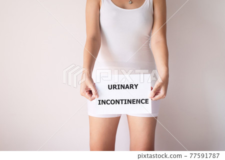 Woman hands holding a white sign with the word urinary incontinence on white background Woman hands holding a white sign with the word urinary incontinence on white background 77591787