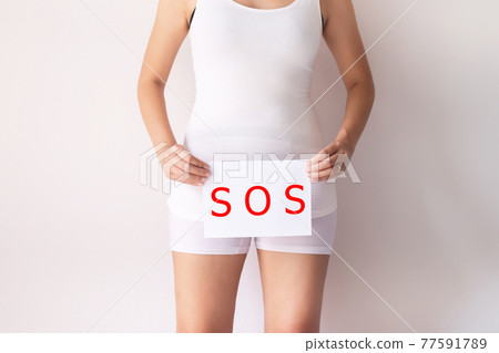 Woman hands holding a white sign with the word sos over crotch on white background Woman hands holding a white sign with the word sos over crotch on white background 77591789