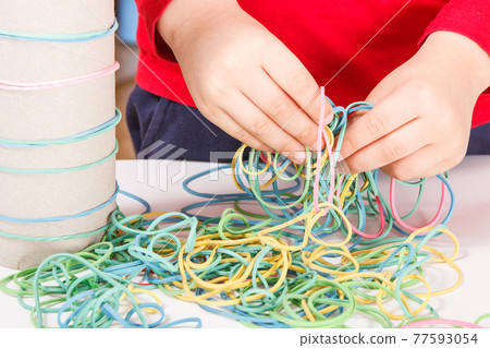 Preschooler playing with rubber erasers and cardboard roll. Development of kids motor skills 77593054