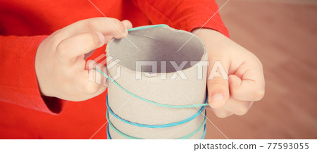 Little boy putting rubber bands or erasers on cardboard roll 77593055