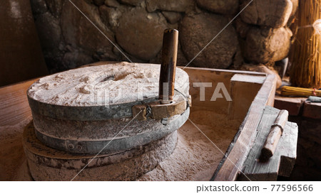 An ancient hand mill made of stones and wood. Flour grinding device 77596566