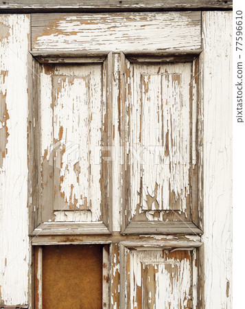 Close-up view of old wooden door texture with peeling white paint. Close-up view of old wooden door texture with peeling white paint. 77596610