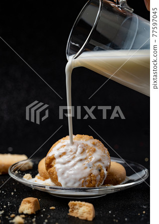 Cookies being topped with milk. Cookies being topped with milk. 77597045